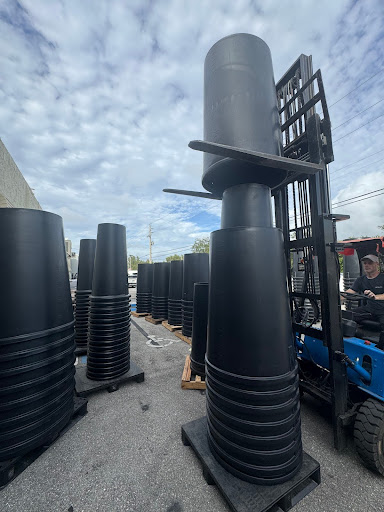 Stacked plastic debris chute sections being moved with a forklift at a construction equipment yard