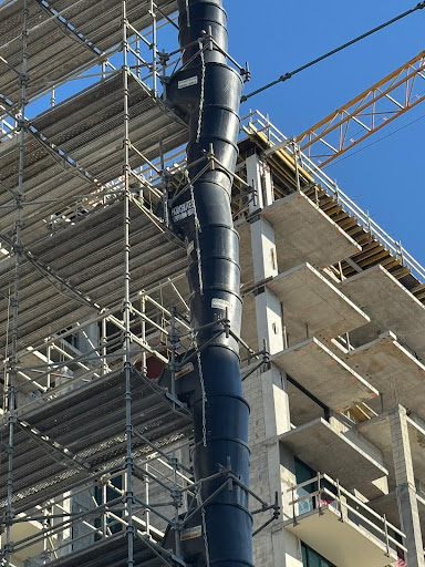 Vertical debris chute system installed on scaffolding for controlled waste removal from upper floors
